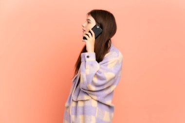 Pembe arka planda izole edilmiş genç Ukraynalı bir kız cep telefonuyla sohbet ediyor.