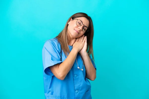中年妇女外科医生在蓝色背景下被隔离 以安稳的表情做睡眠姿势 — 图库照片