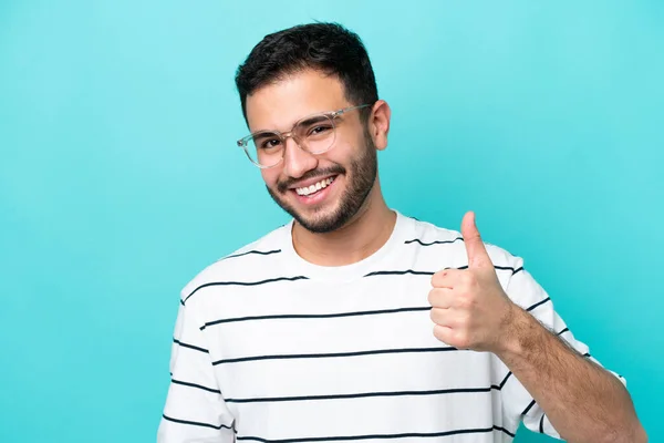Jonge Braziliaanse Man Geïsoleerd Blauwe Achtergrond Met Bril Met Duim — Stockfoto