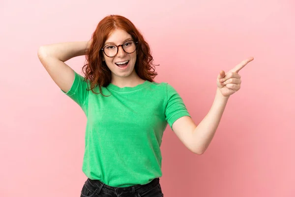 Adolescente Rossa Ragazza Isolato Sfondo Rosa Sorpreso Puntando Dito Verso — Foto Stock