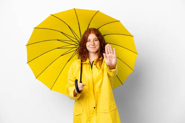 ティーンRedhead女の子レインプルーフコートと傘隔離上のホワイトバックグランド作るストップジェスチャー — ストック写真
