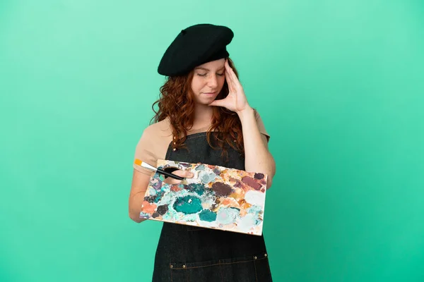 Teenager Κοκκινομάλλα Καλλιτέχνης Κρατώντας Μια Παλέτα Απομονωμένη Πράσινο Φόντο Πονοκέφαλο — Φωτογραφία Αρχείου