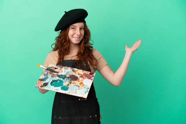 Teenager Redhead Artist Holding Palette Isolated Green Background Extending Hands — Stock Photo, Image