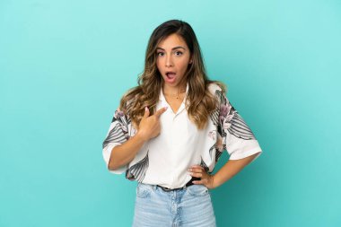 İzole edilmiş mavi arka planı olan genç bir kadın kendini işaret ediyor.