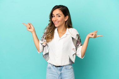 Soyutlanmış mavi arka planda genç bir kadın parmak uçlarında ve mutlu.