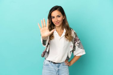 İzole edilmiş mavi arka plan üzerinde genç bir kadın parmaklarıyla beşi sayıyor