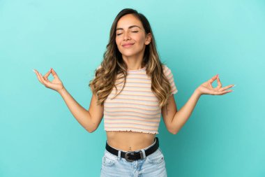 Zen pozunda soyutlanmış mavi arka planı olan genç bir kadın.