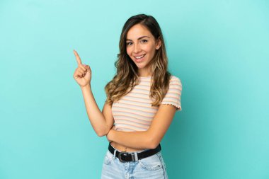 Soyutlanmış mavi arka plan mutlu ve dik duran genç bir kadın.