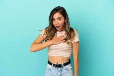 İzole mavi arka plan üzerinde genç kadın sürpriz ve doğru bakarken şok