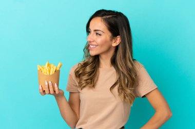İzole edilmiş arka planda kızarmış cipsleri tutan genç bir kadın.