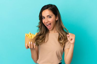 Kızarmış cipsleri arka planda tutan genç bir kadın galibiyeti kutluyor.