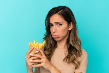 İzole edilmiş arka planda kızarmış cips tutan genç bir kadın.