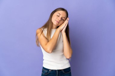 Genç Litvanyalı bir kadın mor arka planda izole edilmiş bir şekilde uyku jesti yapıyor.