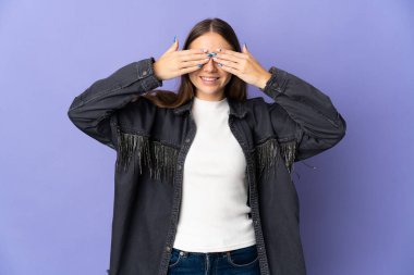 Genç Litvanyalı bir kadın, mor arka planda izole edilmiş, gözleri kaplanmış ve gülümsüyor.