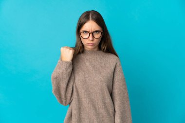 Genç Litvanyalı kadın mutsuz bir ifadeyle mavi arka planda izole edilmiş.