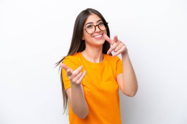 Beyaz arka planda izole edilmiş genç beyaz kadın şaşırmış ve ön tarafı işaret ediyor.