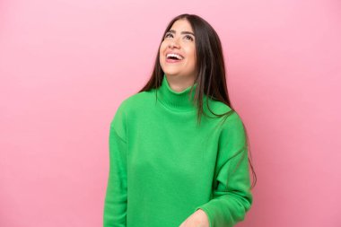 Pembe arka planda izole edilmiş genç beyaz kadın gülüyor.