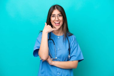 Young nurse caucasian woman isolated on blue background making phone gesture. Call me back sign