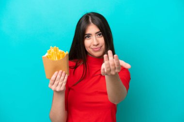 Fransız kızartması yakalayan beyaz bir kadın mavi arka planda izole edilmiş bir şekilde el ele gelmeye davet ediyor. Gelmene sevindim.