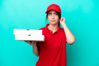 İş üniformalı bir pizzacı kadın mavi arka planda izole edilmiş pizza kutularını alıyor.