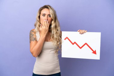 Mor arka planda izole edilmiş genç Brezilyalı kadın elinde azalan bir istatistik okuyla şaşırmış ifade ile bir işaret tutuyor.