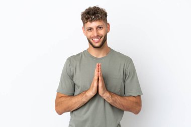 Beyaz arka planda izole edilmiş beyaz, yakışıklı genç bir adam avuç içlerini bir arada tutuyor. İnsan bir şey ister.