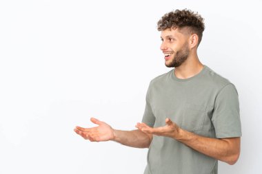 Beyaz arka planda beyaz tenli yakışıklı bir genç. Sürpriz bir ifadeyle yan yana bakarken.