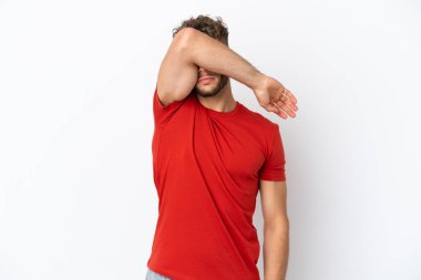 Beyaz arka planda izole edilmiş beyaz tenli yakışıklı adam gözlerini elleriyle kapatıyor.