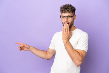 Teslimat beyaz adam mor arka planda izole edildi. Sürpriz bir ifadeyle.