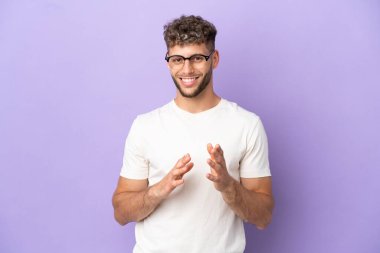 Mor arka planda izole edilmiş beyaz bir adam sunumdan sonra bir konferansta alkışlıyor.