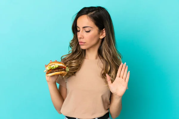 Jeune Femme Tenant Hamburger Sur Fond Isolé Faisant Geste Arrêt — Photo
