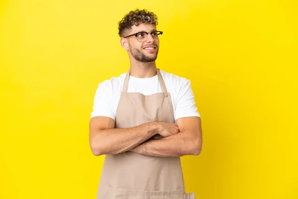 Restaurant Waiter Blonde Man Isolated Yellow Background Looking While Smiling — Zdjęcie stockowe