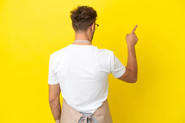 Restaurant Waiter Blonde Man Isolated Yellow Background Pointing Back Index — Foto Stock