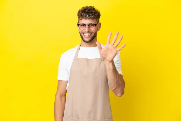Restauracja Kelner Blondynka Człowiek Odizolowany Żółtym Tle Licząc Pięć Palcami — Zdjęcie stockowe