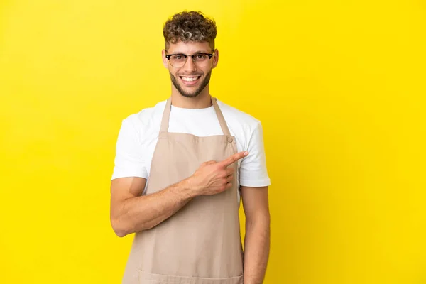 Restauracja Kelner Blondynka Człowiek Izolowany Żółtym Tle Wskazując Stronie Przedstawić — Zdjęcie stockowe