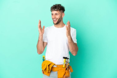 Genç elektrikçi sarışın adam, yeşil arka planda izole edilmiş, şaşırmış bir yüz ifadesi var.