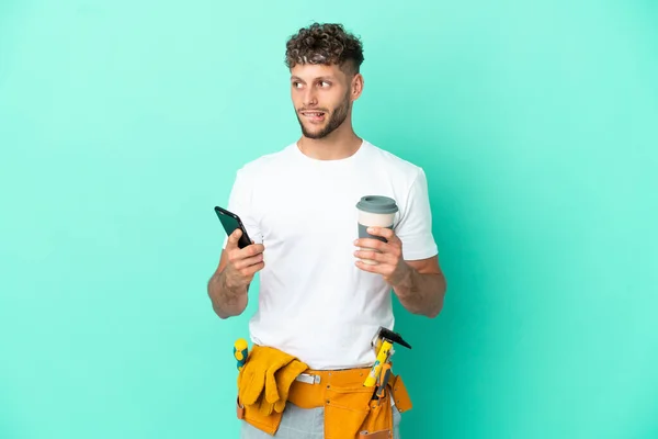 Young Electrician Blonde Man Isolated Green Background Holding Coffee Take — Φωτογραφία Αρχείου