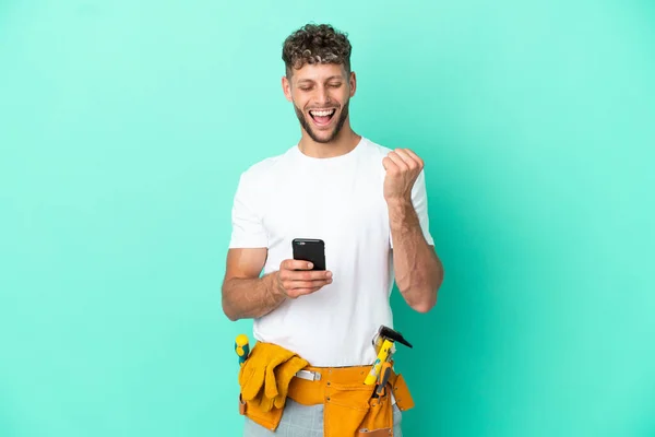 Young Electrician Blonde Man Isolated Green Background Phone Victory Position — Stok fotoğraf