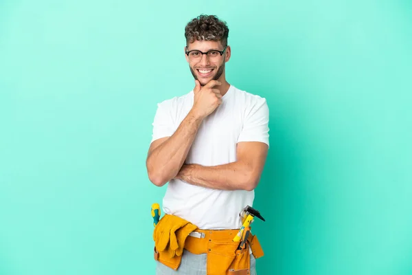 Νεαρός Ηλεκτρολόγος Ξανθός Άνδρας Απομονωμένος Πράσινο Φόντο Γυαλιά Και Χαμογελώντας — Φωτογραφία Αρχείου