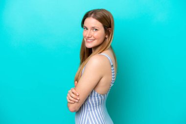 Yaz tatillerinde mayolu mavi arka planda izole edilmiş genç bir kadın.