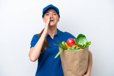Genç teslimatçı kadın beyaz arka planda izole edilmiş, ağzı açık bir şekilde bağırarak bir paket yemek alıyor.