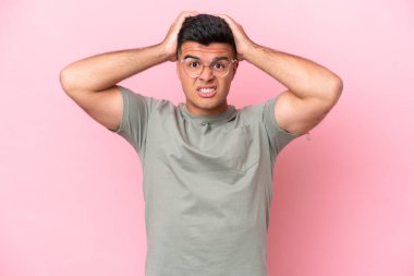 Pembe arka planda izole edilmiş genç, beyaz, yakışıklı bir adam gergin hareketler yapıyor.