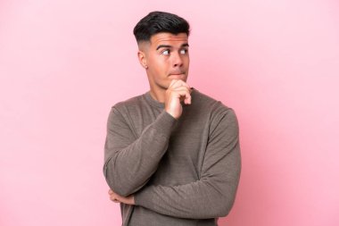 Pembe arka planda soyutlanmış beyaz, yakışıklı genç bir adam. Şüpheleri ve düşünceleri var.