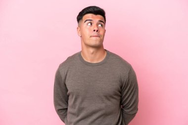 Beyaz tenli yakışıklı adam pembe arka planda izole edilmiş ve yukarı bakıyor.