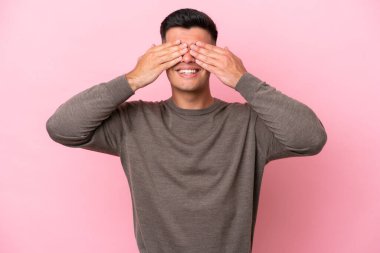 Pembe arka planda soyutlanmış beyaz tenli yakışıklı bir adam. Gözleri kapalı ve gülümsüyor.