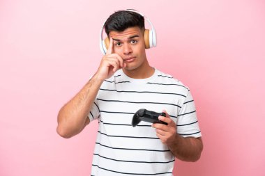 Pembe arka planda izole edilmiş bir bilgisayar oyunu kontrolörüyle oynayan genç yakışıklı bir adam bir fikir düşünüyor.