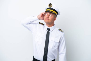 Airplane pilot caucasian man isolated on white background having doubts and with confuse face expression