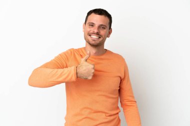 İzole edilmiş beyaz arka planda Brezilyalı bir adam baş parmak hareketi yapıyor.