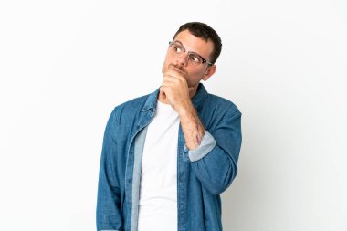 İzole edilmiş beyaz arka planı olan Brezilyalı adamın şüpheleri ve kafası karışmış yüz ifadesi var.