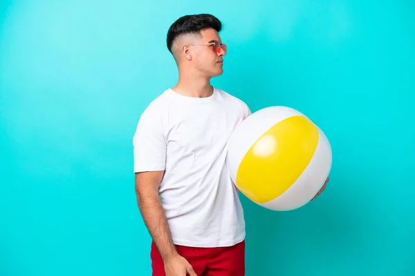 Young Caucasian Man Holding Beach Ball Isolated Blue Background Looking — ストック写真